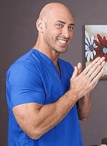 a man in a blue scrub top is clapping his hands in front of a painting .