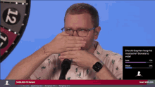 a man covering his mouth with his hands in front of a roulette wheel with the number 12 on it