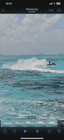 a phone screen shows a video of a person on a jet ski