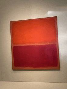 a red and orange painting is hanging on a wall