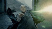 a bald man in a cape is casting a spell with a green light coming out of his hand