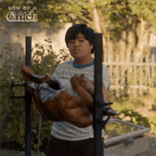 a boy is holding a large piece of meat in front of a sign that says son of a gift