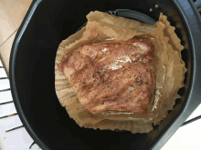 a piece of meat is sitting in an air fryer on a piece of brown paper