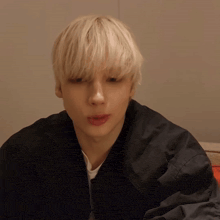 a young man with blonde hair is wearing a black jacket and a white shirt