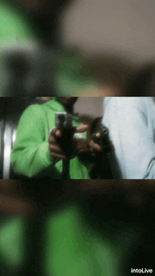 a person in a green jacket is holding a gun in a blurry photo taken by intolive