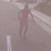 a naked man is walking down a street holding a large pole