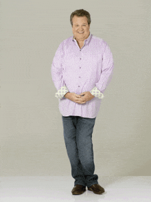 a man wearing a purple shirt and blue jeans