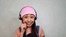 a woman wearing headphones and a pink hat smiles