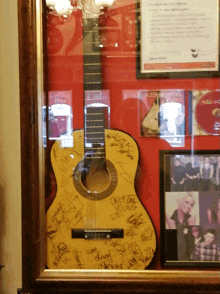 a guitar in a display case has signatures on it including one that says " only the young "