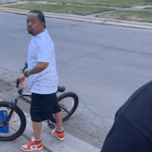 a man standing next to a bicycle wearing nike shoes