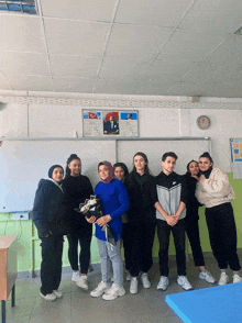 a group of people posing for a picture in a classroom with a clock on the wall