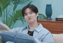 a man sitting on a couch with a blue pillow