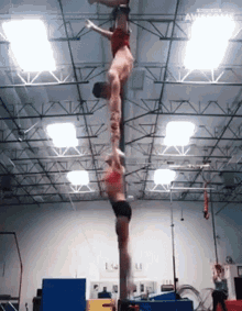 a man and a woman are doing a handstand on a pole in a gym with the words awesome behind them