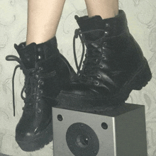 a pair of black boots are sitting on a speaker