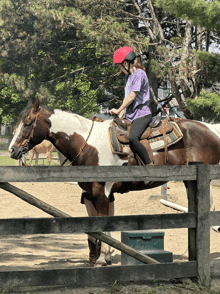 a woman in a red helmet rides a brown and white horse