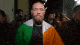 a man with a beard is wearing an irish flag jacket and walking through a tunnel .