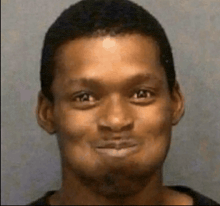a man is smiling and making a funny face in a mugshot .