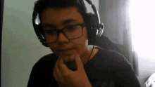 a boy wearing glasses and headphones has his hand on his face