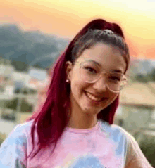 a young girl with red hair and glasses is smiling for the camera .