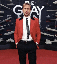 a man in a red suit and tie is standing in front of a sign that says " the gray "