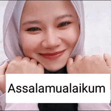 a woman in a hijab is smiling with a sign that says assalamualaikum on it