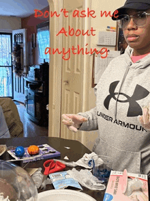 a woman wearing a gray under armour sweatshirt stands at a table