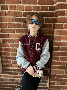 a young boy wearing sunglasses and a san francisco varsity jacket