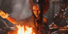 a woman with a feathered headdress is standing in front of a fire