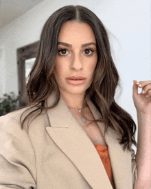 a woman wearing a tan jacket and a necklace