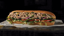 a tuna sandwich with lettuce tomatoes and olives