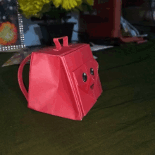 a red purse with a smiley face on the front sits on a table