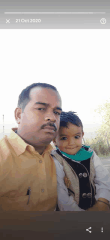 a man is holding a small child in his arms and the date of the photo is 21 oct 2020