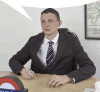 a man in a suit and tie sits at a desk in front of a map