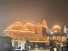 a large temple is lit up at night with a few people standing in front of it