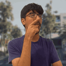 a man wearing glasses and a purple shirt is covering his nose with his hand