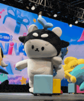 a group of stuffed animals are on a stage in front of a large screen that says g-mm