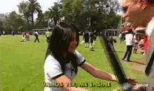 a woman in a white shirt is talking to a man on a field with the words " vamos ver me ensine " above her