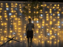 a shirtless man is standing in front of a curtain with lights on it