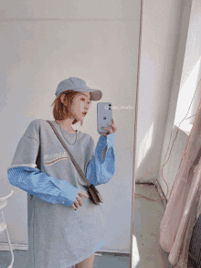 a woman taking a picture of herself in front of a mirror with a phone that says ' @isu_studio ' on it