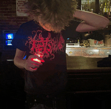 a man wearing a shirt that says ' heavy metal ' on it is holding a glass