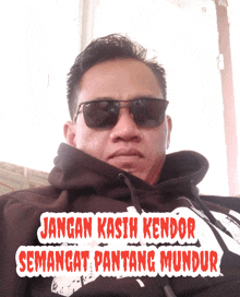 a man wearing sunglasses and a hoodie with the words jangan kasih kendor semangat pantang mundur