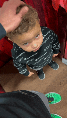 a little boy wearing a black champion sweater looks up at the camera