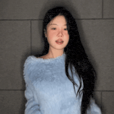 a woman with long black hair is wearing a blue furry sweater