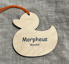 a wooden duck shaped tag with the name morpheus on it