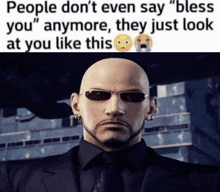 a bald man in a suit and tie with sunglasses says people don 't even say " bless you " anymore