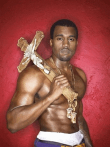 a shirtless man holding a wooden cross with jesus on it