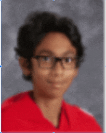 a blurry photo of a young boy wearing glasses and a red shirt