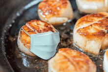 scallops are being cooked in a pan with a face mask on top of them