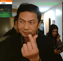 a man giving the middle finger in front of a screen that says " winner "