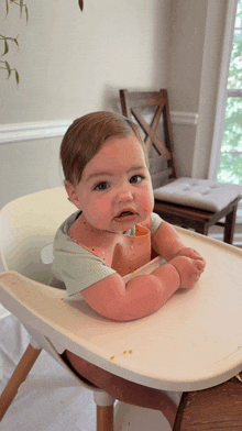 a baby is sitting in a high chair with food on his face